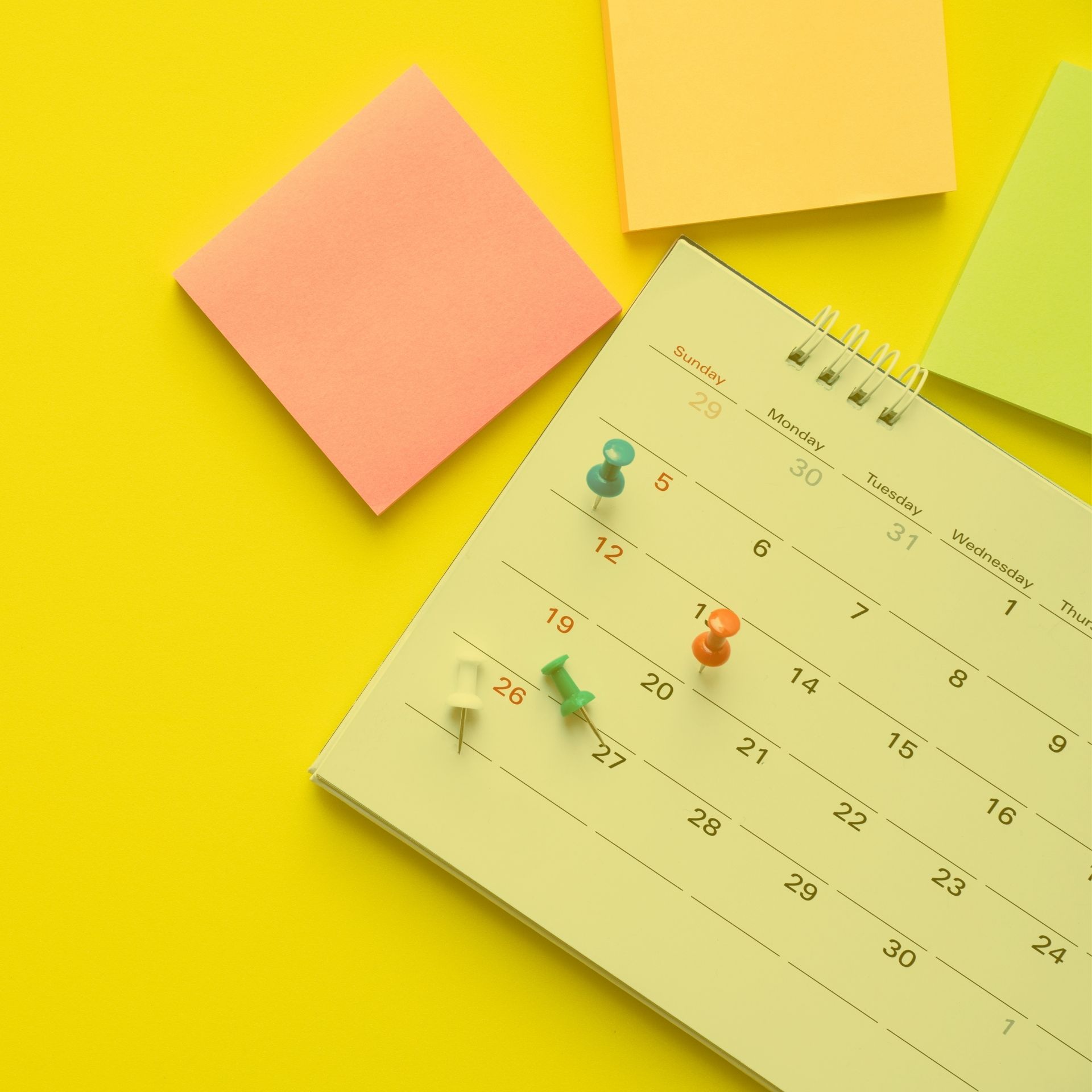 Close up of calendar on yellow background and three post its